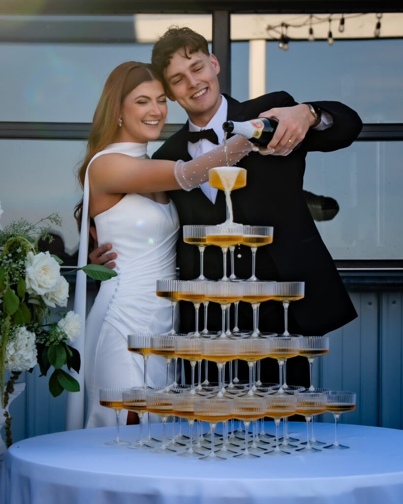 Iowa couple pouring a Champagne tower on their wedding day at 1868 Farmhouse Iowa wedding venue